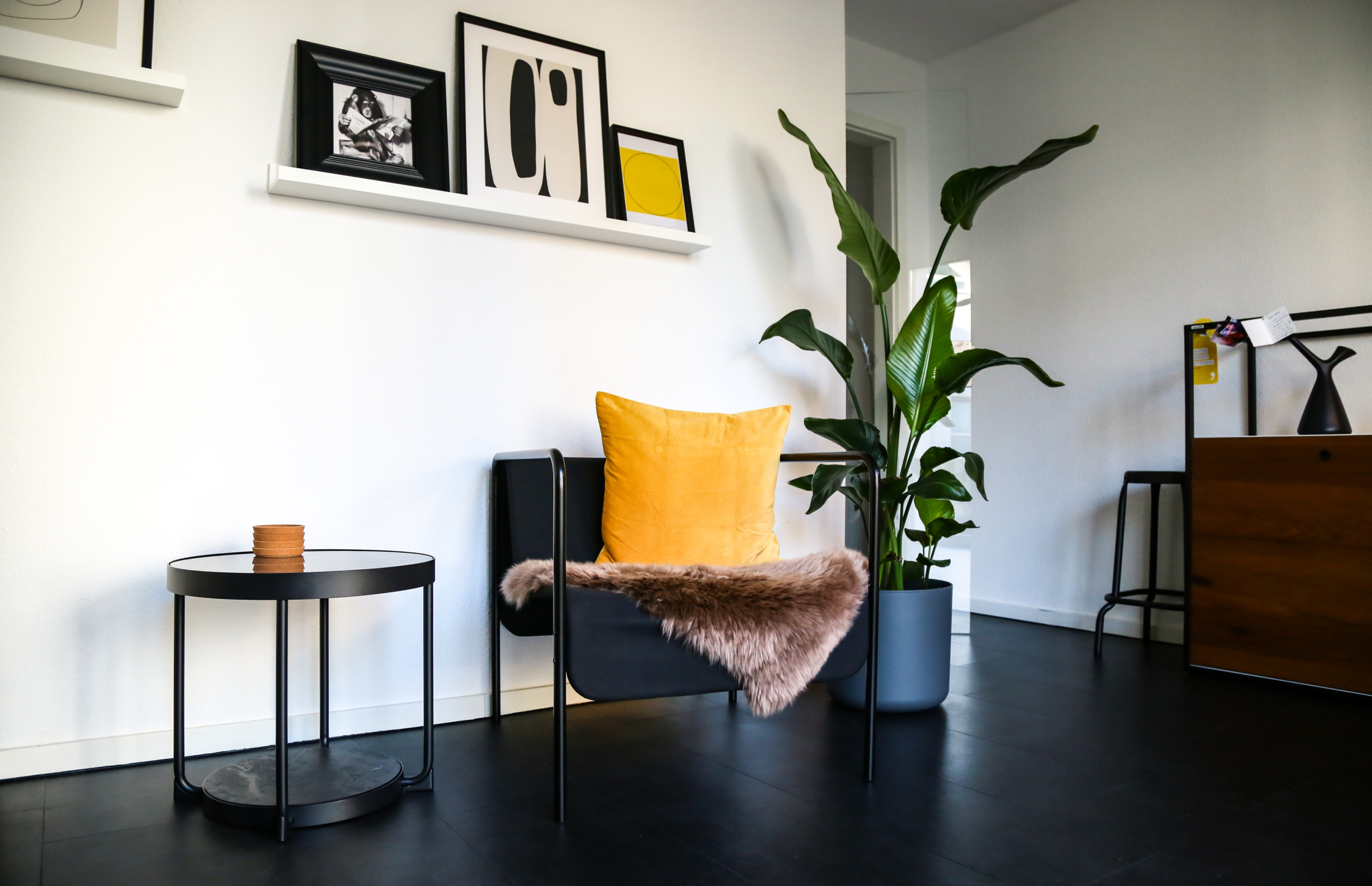 Foto von einem der Büros mit Sessel, Zimmerpflanze, Beistelltisch und Bildern an der Wand